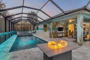 Luxury screened pool and spa with fire pit, tropical mural, and outdoor entertainment area.
