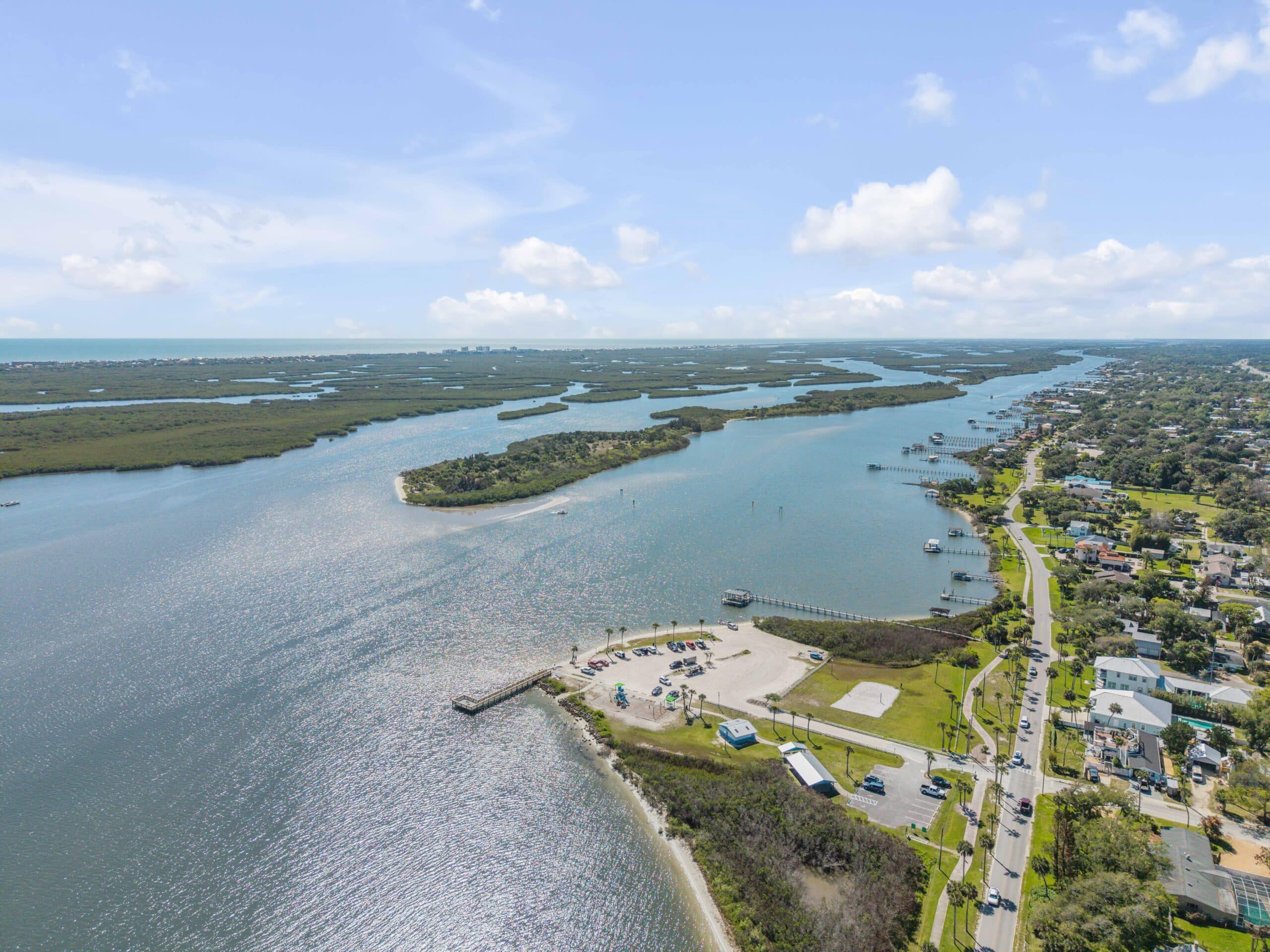 Aerial view of a coastal waterway with homes and a park, ideal for local living real estate.