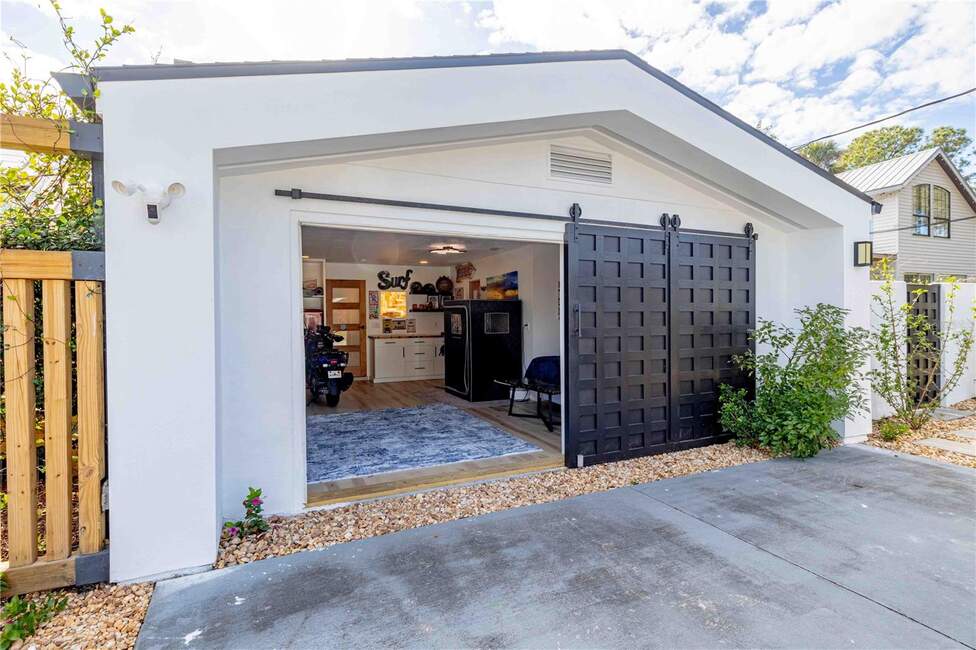 Modern garage with open barn doors revealing a kitchen and motorcycle at 500 S Riverside Dr